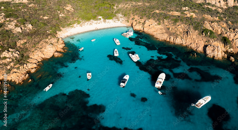 View from above, stunning aerial view of Mortorio island with a beautiful white sand beach and some boats and yachts floating on a turquoise, crystal clear water. Sardinia, Italy.