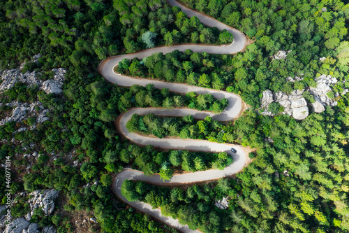 Fotografie View from above, stunning aerial view of a serpentine road surrounded by green pine trees