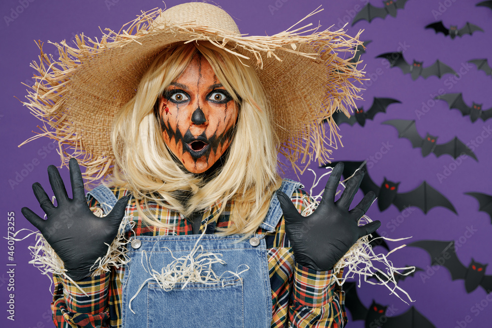 Young scary creepy woman 20s with Halloween makeup mask in straw hat  scarecrow costume spread hands say booo isolated on plain dark purple  background studio portrait Celebration holiday party concept. Stock-foto