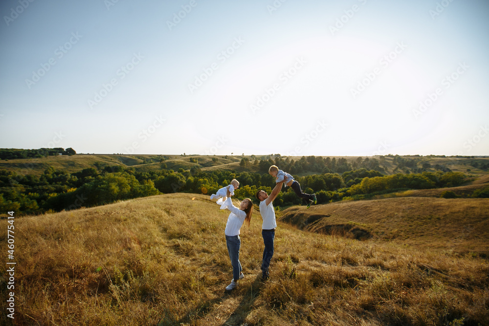mom and dad raised the children above their heads against the backdrop of nature mom and dad raised the children above their heads against the backdrop of nature