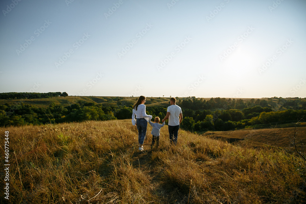 mom and dad run across the field holding their son's hands mom and dad run across the field holding their son's hands