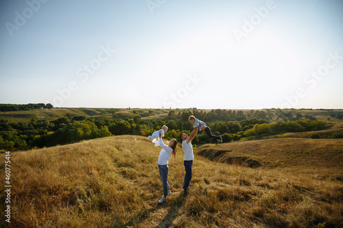 mom and dad raised the children above their heads against the backdrop of nature