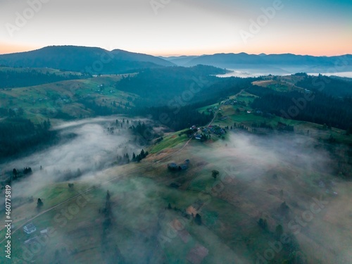 Fog in the mountain valley at dawn. Ukrainian Carpathians in the morning in the haze. Aerial drone view.