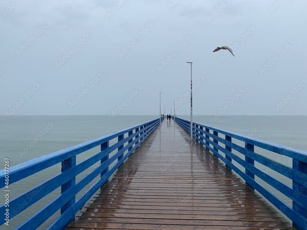 Empty wooden pier at the sea, rainy day, gray sky, moody atmosphere 