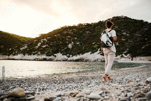 Caucasian male walking along the beach wit backpack at sunrise © Prins Productions