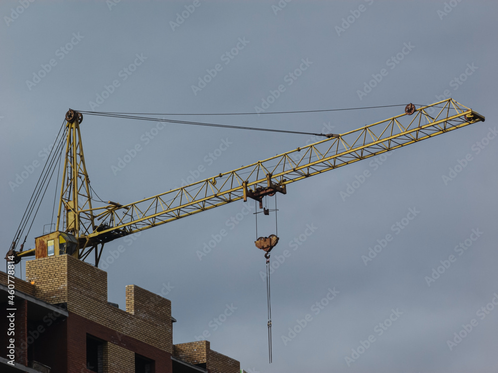Yellow crane on the background of a building under construction.