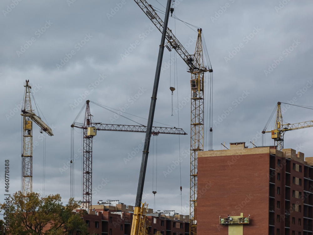 Yellow cranes on the background of buildings under construction. Yellow cranes on the background of buildings under construction.