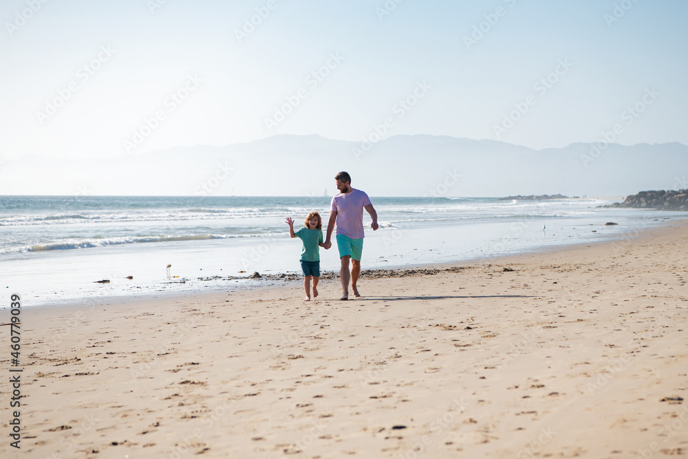 Dad and child holding hands and walk together. Father and son walking on sea. Family travel, vacation, father's day concept.