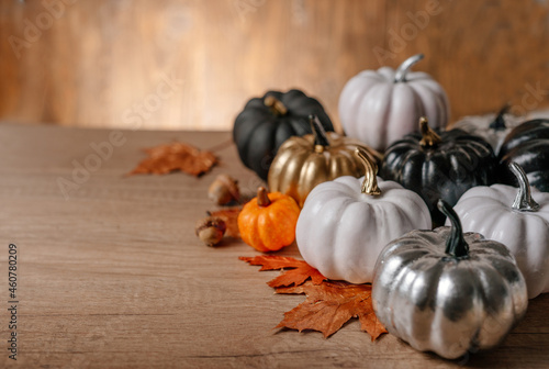 Decorated golden, black and natural pumpkins on wooden background