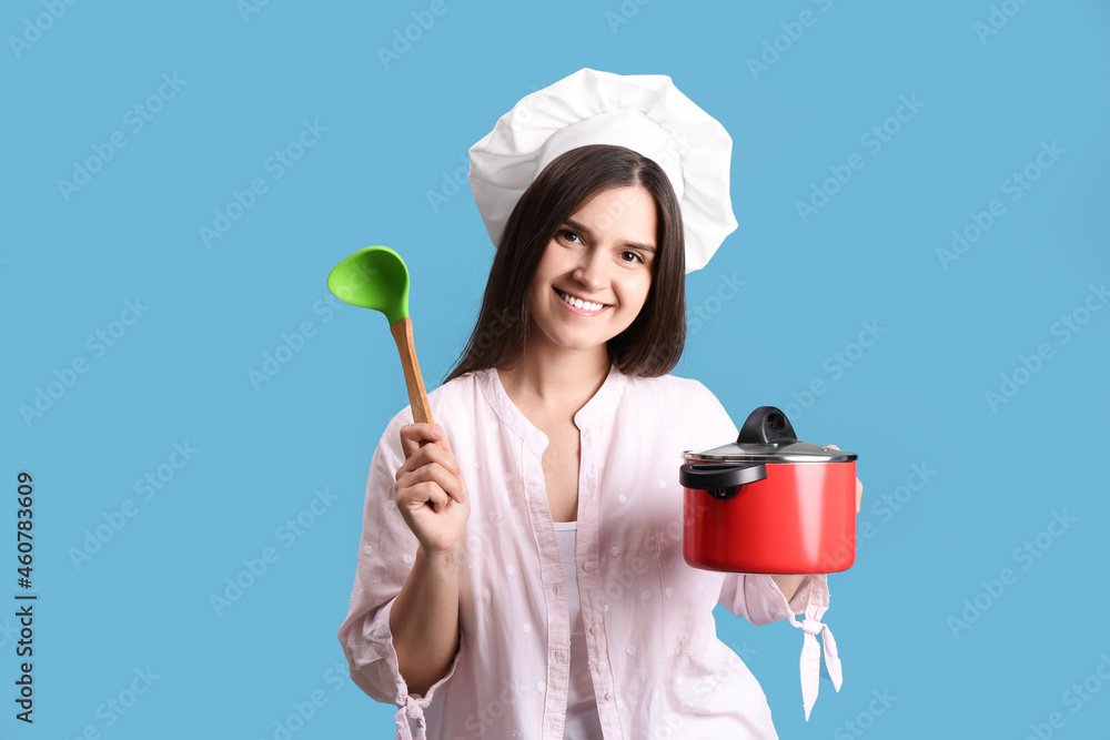 Happy young woman with cooking pot and ladle on light blue background Happy young woman with cooking pot and ladle on light blue background