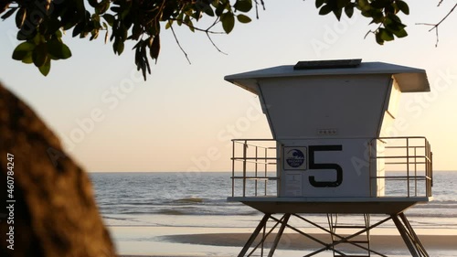 Lifeguard watch tower, sunny sunset beach, Oceanside USA. Rescue station, waterfront watchtower hut and tree leaves, pacific ocean coast atmosphere. California summertime aesthetic, Los Angeles vibes.