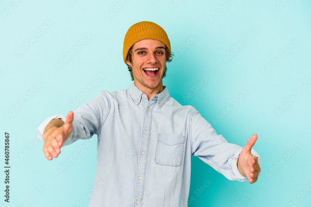 Young caucasian man with make up isolated on blue background showing a welcome expression. Young caucasian man with make up isolated on blue background showing a welcome expression.