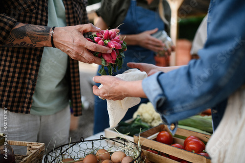 Close up of mans hands buying organic vegetables outdoors at local farmers market.