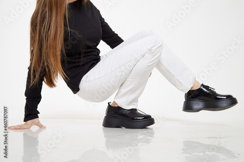 Black female or male patent leather shoes on legs of woman. Shooting for a catalog or an online store. A pair of shoes