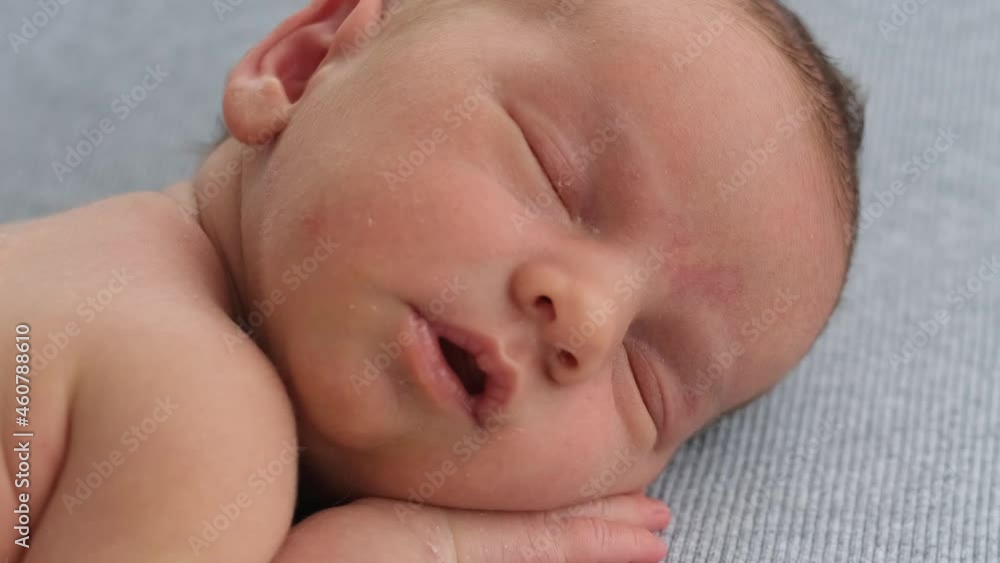 Closeup portrait of newborn baby boy face during sweet sleeping time. Infant holding his hand under his cheek and napping Closeup portrait of newborn baby boy face during sweet sleeping time. Infant holding his hand under his cheek and napping
