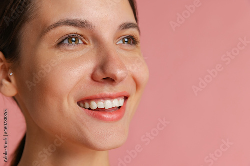 Close-up portrait of young beautiful girl without makeup isolated over pink studio background. Natural beauty concept.