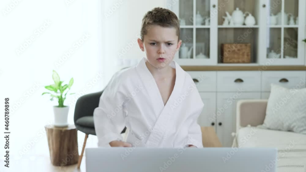 Little boy practicing karate techniques online in front of laptop at home Little boy practicing karate techniques online in front of laptop at home