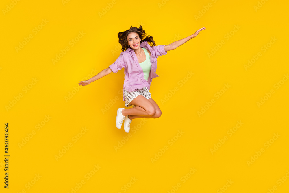 Obraz premium Full body photo of positive happy young woman jump up enjoy hands plane wings isolated on yellow color background
