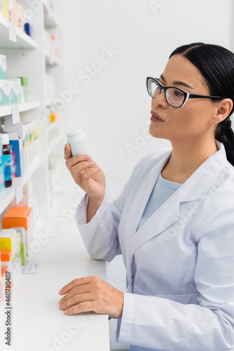 asian pharmacist in white coat holding bottle with medication