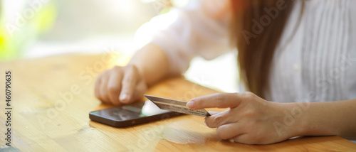 Woman in white shirt hold credit card and touch on mobile phone screen