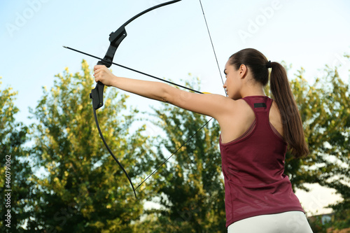 Woman with bow and arrow practicing archery outdoors