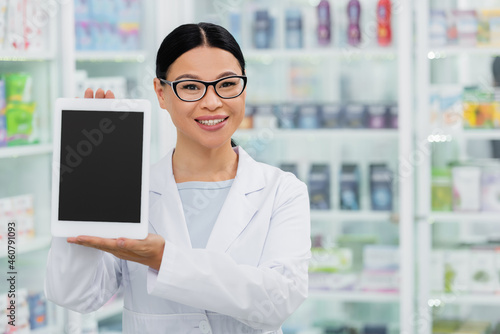 positive asian pharmacist in glasses holding digital tablet with blank screen in drugstore © LIGHTFIELD STUDIOS