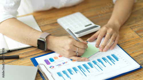 Businesswoman hand using pen and writing business idea lists in post note or sticky note