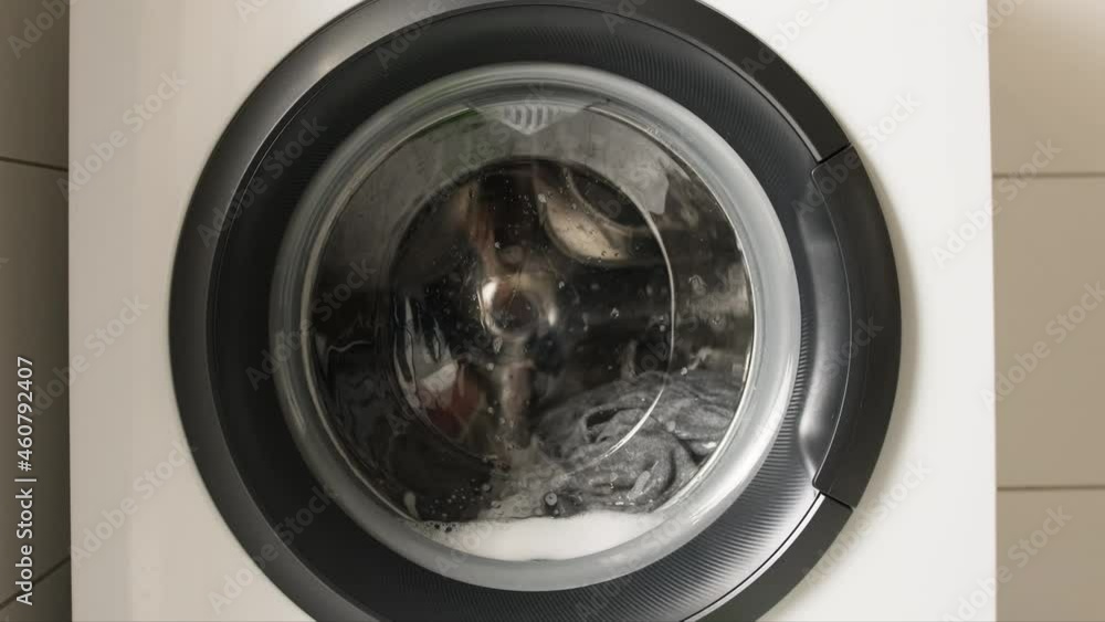 Washing machine working during laundry cycle with clothes inside. Front view Washing machine working during laundry cycle with clothes inside. Front view