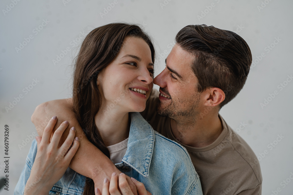 Portrait of happy young couple hugging and looking at each other, on white background.
