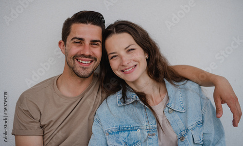 Portrait od happy young couple hugging and looking at camera, on white background.