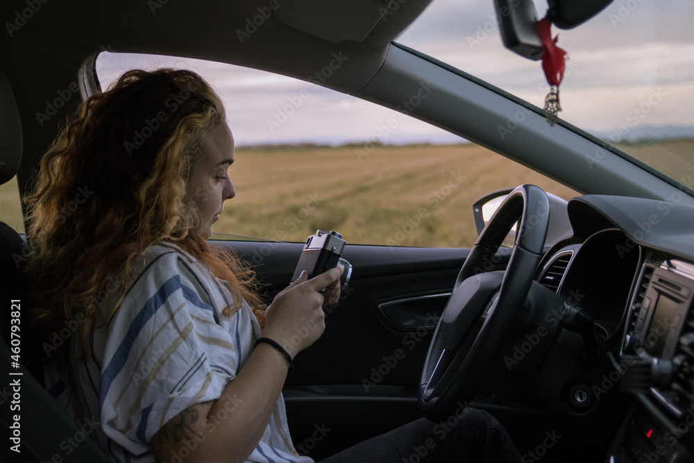 Woman inside her car taking a picture with her analog camera of a landscape in a rice field Woman inside her car taking a picture with her analog camera of a landscape in a rice field