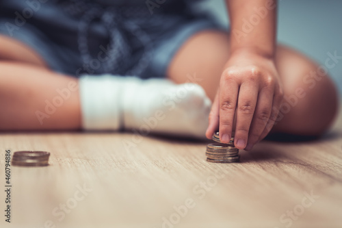 Child sitting with coins on the floor. Children are having fun sorting silver coins. Concept of finance and savings.