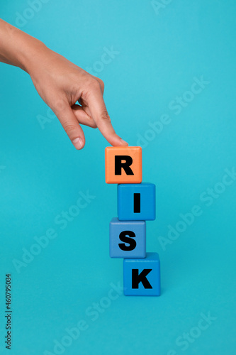 Woman making word Risk with colorful cubes on turquoise background, closeup