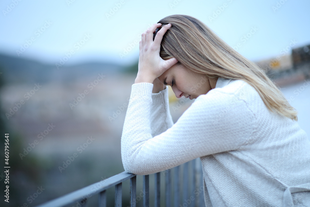 Depressed woman complaining in balcony Depressed woman complaining in balcony