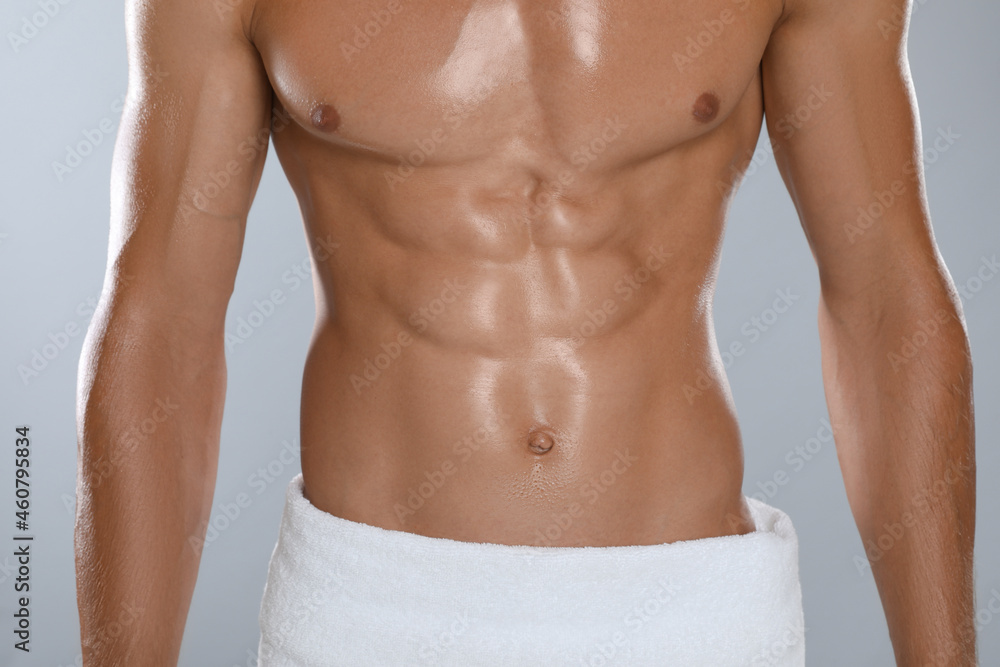 Shirtless man with slim body and towel wrapped around his hips on grey background, closeup Shirtless man with slim body and towel wrapped around his hips on grey background, closeup