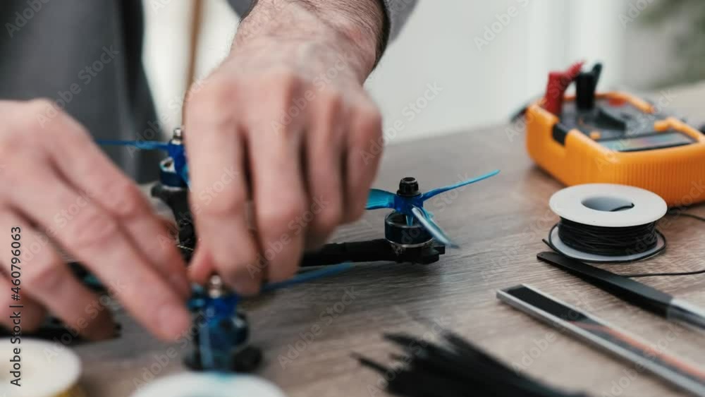Man engineer screws propeller with nut during quadcopter repairing process. Closeup view of table with tools Man engineer screws propeller with nut during quadcopter repairing process. Closeup view of table with tools