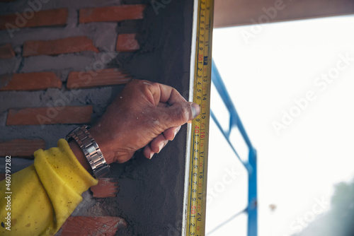    Hand of man using tape measure window with brick wall background. Construction Workers work at construction site.  Worker work Building house concept.