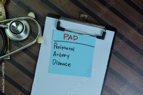 PAD - Peripheral Artery Disease write on sticky notes isolated on Wooden Table.