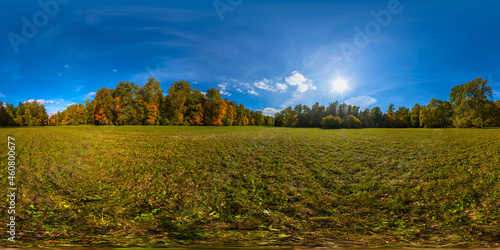 360 by 180 degree spherical panorama of sunny autumnal mowed meadow and yellow forest on its edges with blue sky and clouds. photo