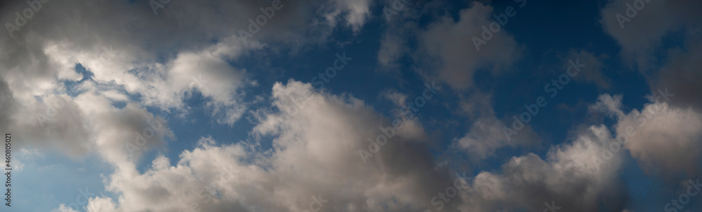 Panoramic image of a summer sky with cumulus clouds and some natural sunlight.