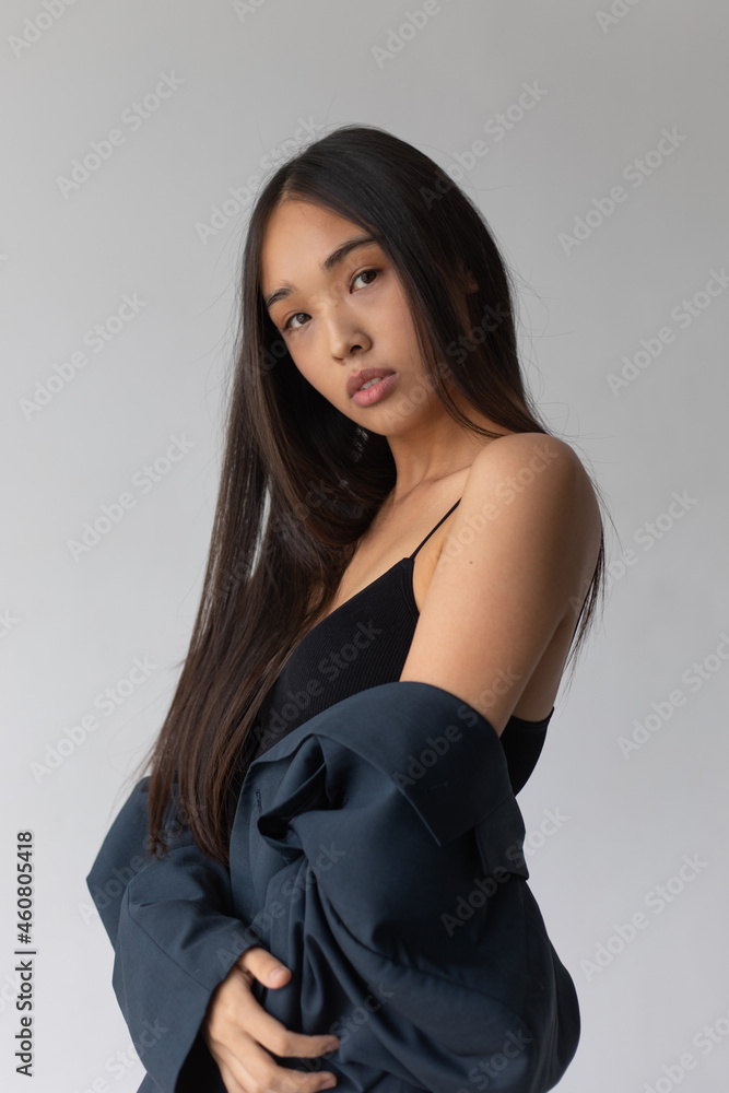Naklejka premium Attractive asian woman in jacket posing on white background.