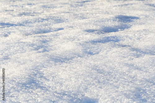 Close-up of fresh shiny snow on the ground on a sunny day. Good as a winter season background. Shallow depth of field.