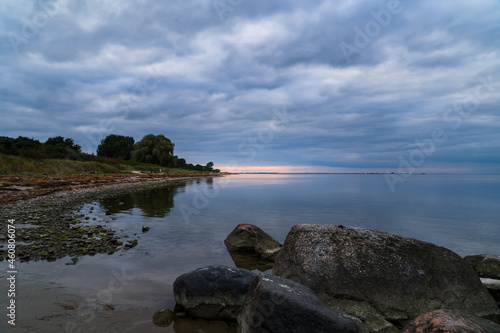 Cloudy sunset at a beach of the baltic sea in Germany with big rocks in the foreground
