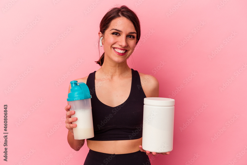 Young caucasian woman drinking a protein shake isolated on pink background Young caucasian woman drinking a protein shake isolated on pink background