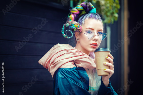 Cool funky young girl with piercing and crazy hair enjoy takeaway coffee on street