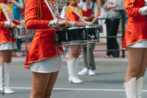 Young girls drummer in red vintage uniform at the parade. Street performance of festive march of drummers girls in red costumes on city street