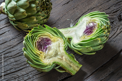 Green and purple artichoke flower edible buds on wooden background. photo