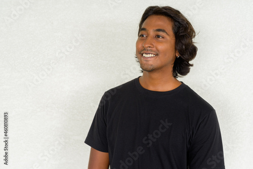 Portrait of handsome young Indian man against plain background