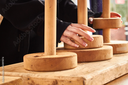 Obraz na plátně Closeup of white woman hands solving the tower of Hanoi puzzle ring stack game