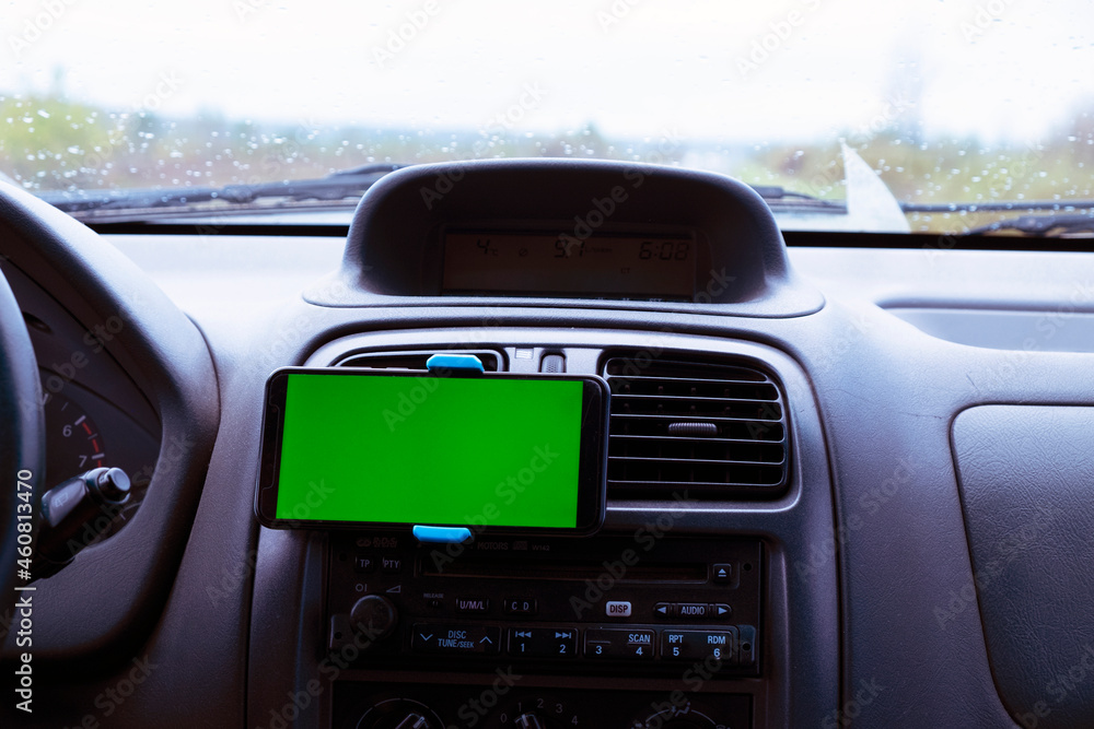 Mobile phone with a green screen on the mount inside the car. Concept application for phone, mock up, location, address search